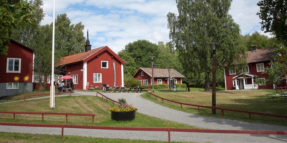 En bondgård med flera gamla hus i olika storlekar. Husen är röda med vita knutar.